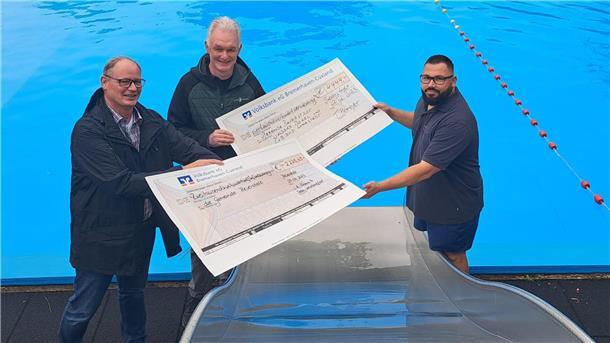 Bokels Ortsvorsteher Stefan Somnitz (links) vom Team Waldbadfest und Thomas Hemeyer von Edeka übergeben im Waldbad Bokel ihre Spendenchecks über insgesamt knapp 6700 Euro an Marcel Curras-Varela, Betriebsleiter der Beverstedter Bäder. 