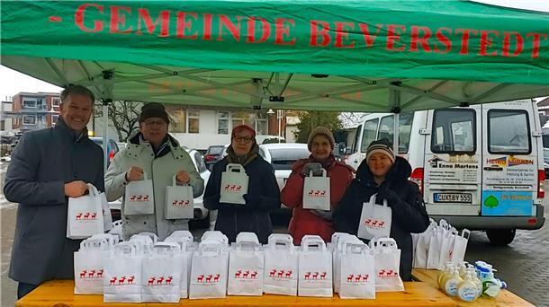 Fünf Personen stehen bei der Aktion "Freude schenken im Advent" an einem Stand, um Geschenktüten zu verteilen