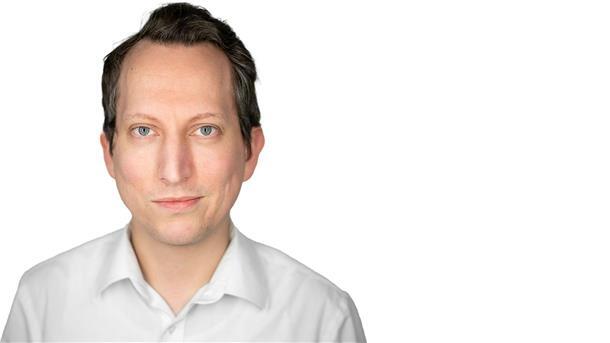 Auf dem Foto ist ein Mann in einem weißen Hemd zu sehen. 