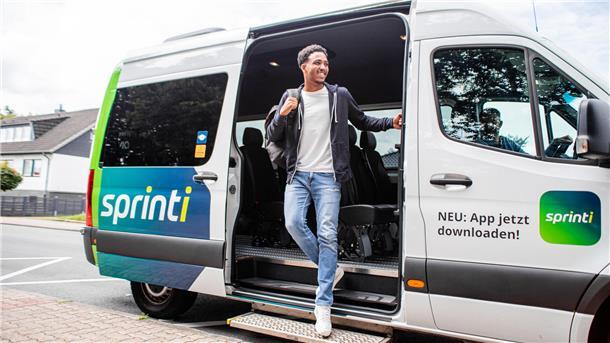 Ein Mann steigt aus einem Kleinbus mit der Aufschrift "sprinti"