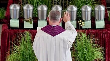 Ein Pastor steht vor sieben Urnen in einer Friedhofkapelle