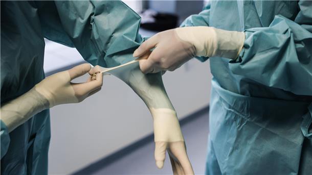 Ärzte ziehen OP-Handschuhe an. 