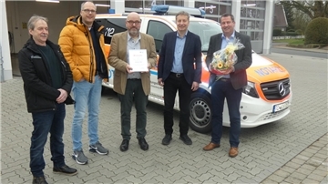 Fünf Männer stehen vor einem Rettungswagen. 