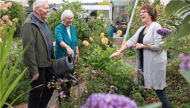 Ein Mann unterhält sich mit zwei Frauen in einem Garten