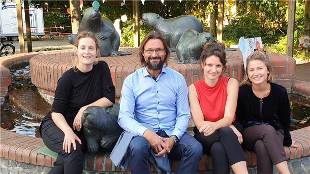 Vier Erwachsene sitzen vor einem Brunnen
