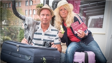 Zwei Urlauber sitzen auf gepackten Koffern