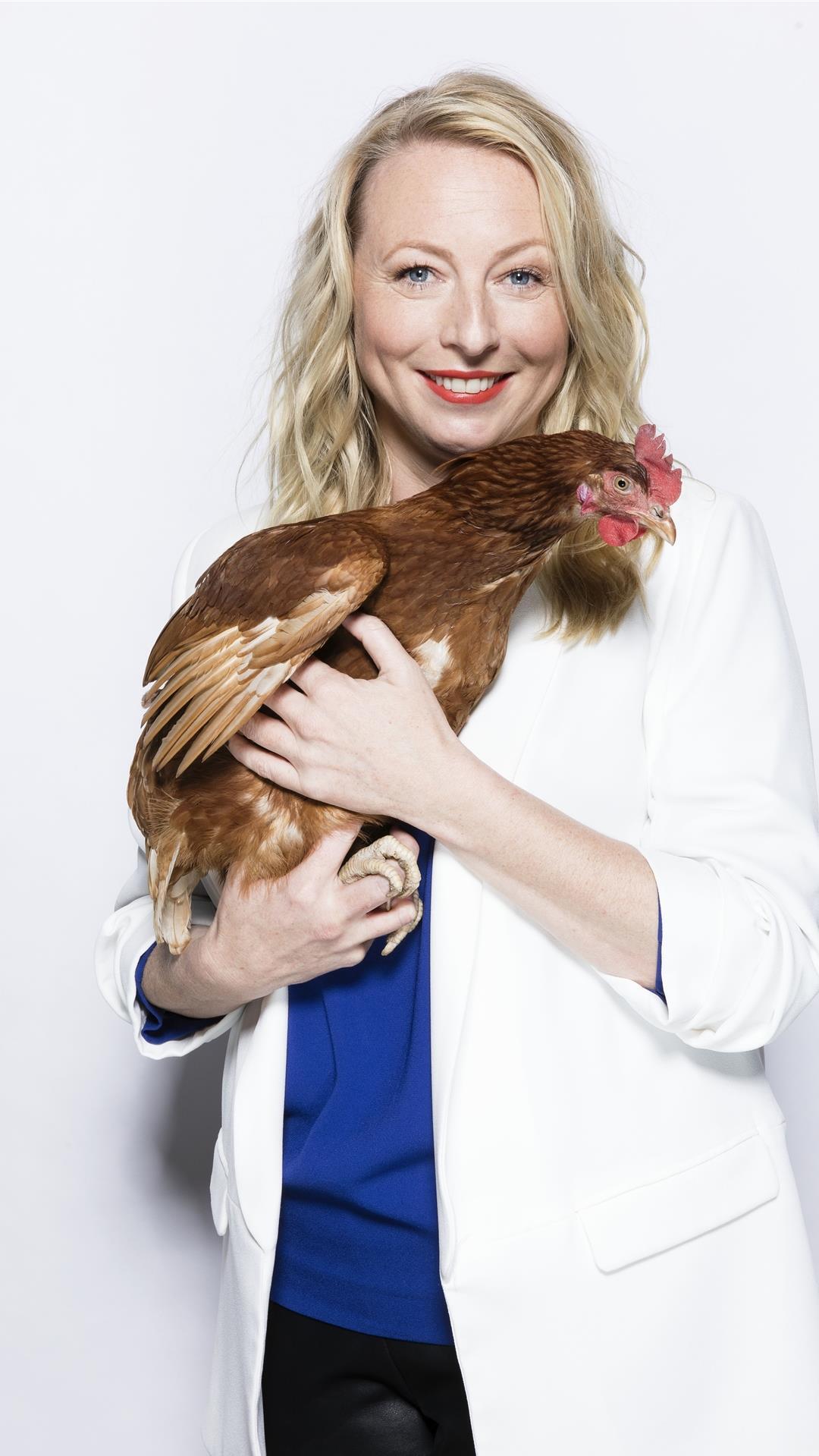 Eine Frau hält ein Huhn im Arm.