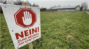 Schild mit der Aufschrift „Nein zum Neubau am Kiebitzberg" auf einer Rasenfläche.