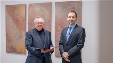 Zwei Männer vor einer Wand Übergabe Ernennungsurkunde