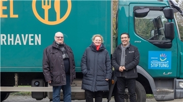 Zwei Männer und eine Frau stehen vor einem Lkw.