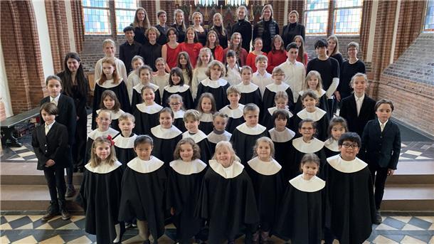 Kinder und Jugendliche haben sich in einer Kirche aufgestellt.