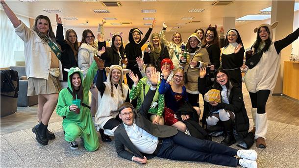 Frauen in Kostümen reißen die Arme hoch, während ihnen ein Mann zu Füßen liegt. Burhave feiert Weiberfastnacht.