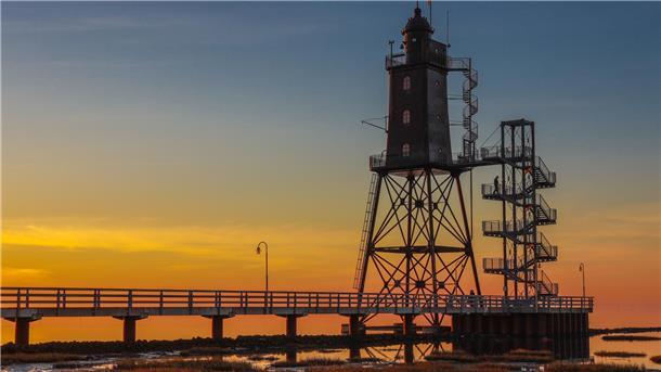 Loxstedter ist Fotomeister der Region Elbe-Weser-Ems **ALT-Text:**  
Historischer Leuchtturm Obereversand in Dorum-Neufeld bei Sonnenuntergang, mit Steg und Treppe im Vordergrund und farbenfrohem Himmel im Hintergrund.
