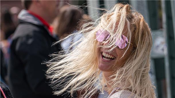Eine Frau mit Kamera lacht in die Sonne