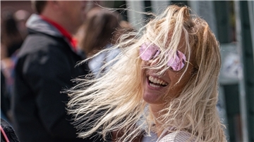 Eine Frau mit Kamera lacht in die Sonne