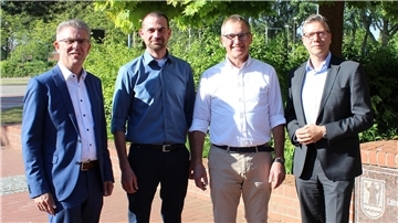 Vier Herren stellen sich zum Gruppenfoto auf. 