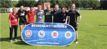 Junge Fußballhelden stehen mit einem Banner auf dem Sportplatz.