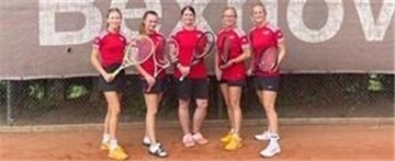 Tennis-Damen stehen mit Schlägern in der Hand aufgereiht auf dem Platz.