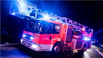 Ein Feuerwehrauto fährt bei Nacht mit Blaulicht.