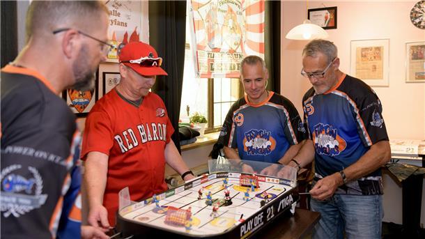 Eishockey-Cup im Tischformat - Fans überbrücken Sommerzeit vier Männer in Sportshirts an einem Stiga-Hockey-Tisch