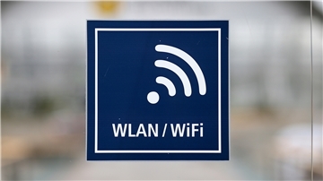 WLAN-Symbol, blaues Schild an Glasscheibe, weiße Schrift auf blauem Grund.