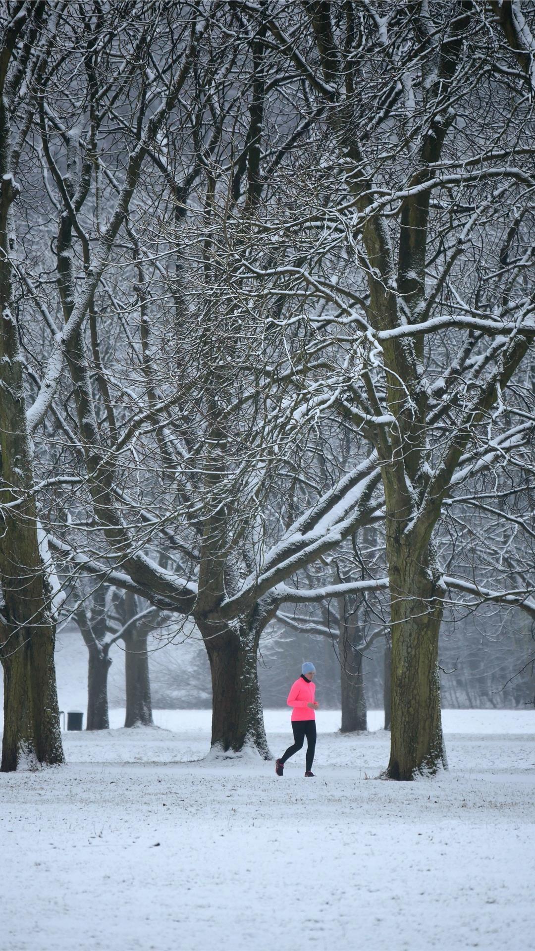 Eine Frau joggt bei Schnee im Wald.