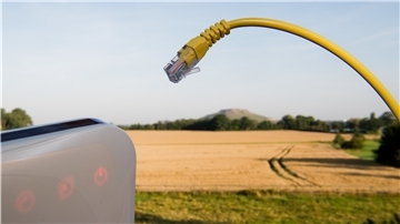 Ein Netzwerkkabel und ein Router vor einem Feld auf dem Land.