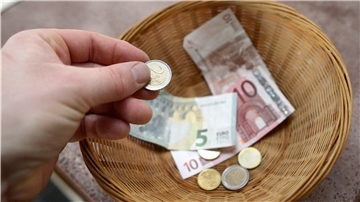 Eine Hand gibt Geld in einen Sammelkorb.