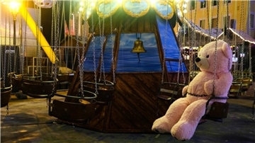 Ein großer Teddybär sitzt in einem Kettenflieger, das auf dem Weihnachtsmarkt in Bremerhaven steht. 