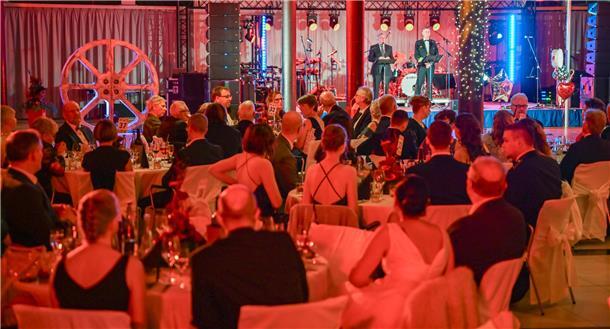 festlich gekleidete Menschen an Tischen sitzend