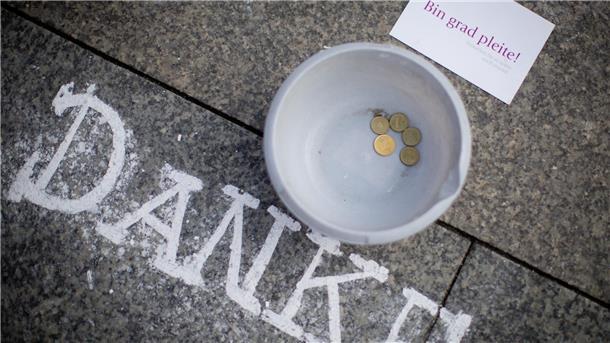 27 Unternehmen pleite: Firmeninsolvenzen in Bremerhaven steigen deutlich an Ein Sammelbehälter mit wenigen Münzen steht auf dem Boden neben einer Postkarte mit der Aufschrift "Bin grad pleite!" und dem Kreide-Schriftzug "Danke"