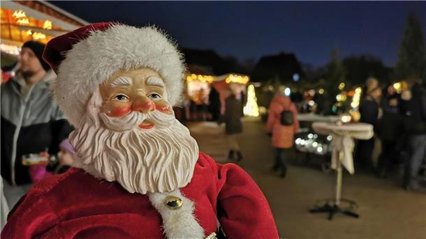 Auf einem Weihnachtsmarkt steht eine Weihnachtsmannfigur