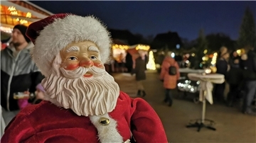 Auf einem Weihnachtsmarkt steht eine Weihnachtsmannfigur