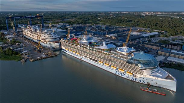 Luftaufnahme der Meyer-Werft in Turku, Finnland: Im Vordergrund liegt das Kreuzfahrtschiff „Star of the Seas“ am Ausrüstungskai, dahinter ein weiteres Schiff der Icon-Klasse im Bau. Die Werftanlagen und Hallen erstrecken sich bis in den Hintergrund.