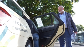 Dieter Schmidt, Inhaber der Rotenburger Firma Julia Reisen, hält einem Fahrgast die Tür auf.