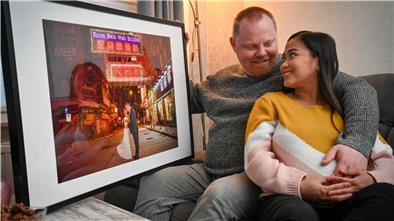 Ein Pärchen sitzt auf einem Sofa und schaut auf ein Foto.