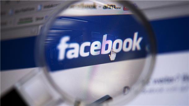 Facebook sperrt dein Konto und du weißt nicht warum Blick durch eine Lupe auf das Logo des sozialen Netzwerkes Facebook.