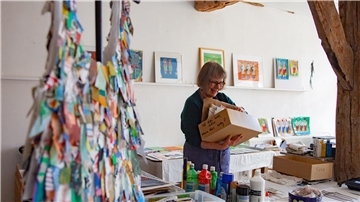 Eine Frau steht in einem Atelier und schaut in eine Kiste.