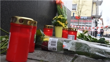 Blumen und Kerzen liegen und stehen in der Nähe eines Tatortes am Heumarkt in Hanau.