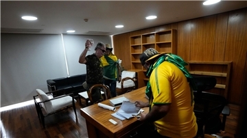 Bolsonaro-Anhänger wühlen sich in einem Büro des Palacio do Planalto, dem offiziellen Sitz des brasilianischen Präsidenten, durch Papiere.