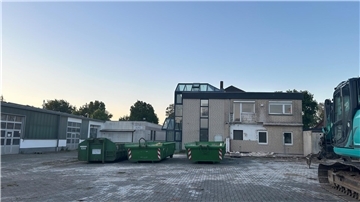 Drei Container stehen vor einem Haus.