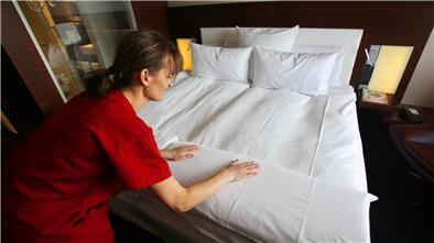 Frau bringt Hotelbetten in Ordnung.