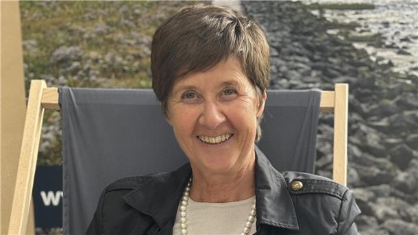 Eine braunhaarige Frau blickt lächelnd in die Kamera. 