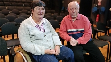 Zwei Menschen sitzen im Theatersaal.