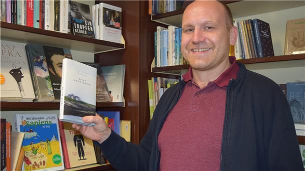 Ein Buchhändler hält ein Buch in der Hand.