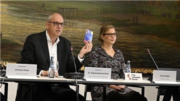 Andreas Bovenschulte sitzt an einem Tisch und präsentiert zusammen mit der Projektreferentin Sarah Göttges die Freikarte.
