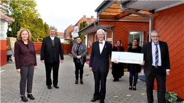 Bürgermeister Carsten Seyfarth (rechts) überreichte Fred Memenga einen Stich mit einer historischen Ansicht des Nordenhamer Weserufers. Neben den beiden zeigt das Bild (von links) Maria Groß-Bölting, Pfarrer Karl Jasbinschek, Dorette Wittje, Süntka Janßen und Denise Smith, allesamt ehemalige und aktuelle Aktive des Arbeitslosenzentrums.