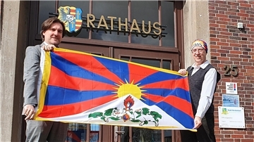Bürgermeister Nils Siemen (links) und Rüdiger Pilny mit der Tibet-Flagge vor dem Nordenhamer Rathaus