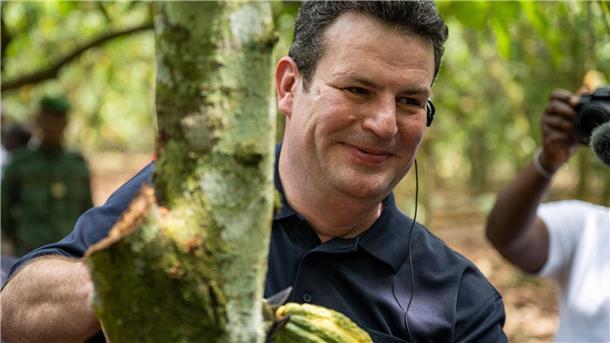 Bundesarbeitsminister Hubertus Heil erntet auf einer Kakaoplantage in Agboville an der Elfenbeinküste eine reife Kakao-Schote.