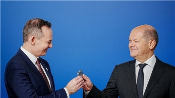 Bundeskanzler Olaf Scholz (r, SPD) übergibt an Volker Wissing (FDP), Bundesminister für Verkehr und Digitales, eine Komponente eines Schaltschranks weiter.